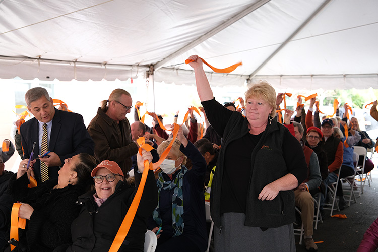 President and CEO Julie LaFontaine leads a community ribbon- cutting, involving the whole crowd, at Saturday’s ceremony at The Open Door. (Photo Courtesy of The Open Door) 