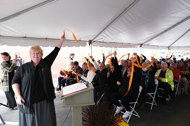 President and CEO Julie LaFontaine (left) waving a piece of orange ribbon after the ribbon-cutting.  (Photo Courtesy of The Open Door) 